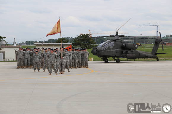 부대원들이 부대기를 들고 입장하고 있다. 부대원 뒤로 미군의 주력 아파치 헬기가 도열해 있다. 